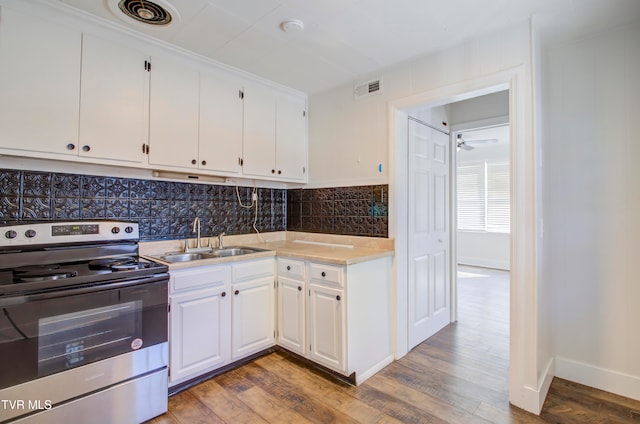 kitchen featuring stainless steel electric stove, wood finished floors, visible vents, and a sink