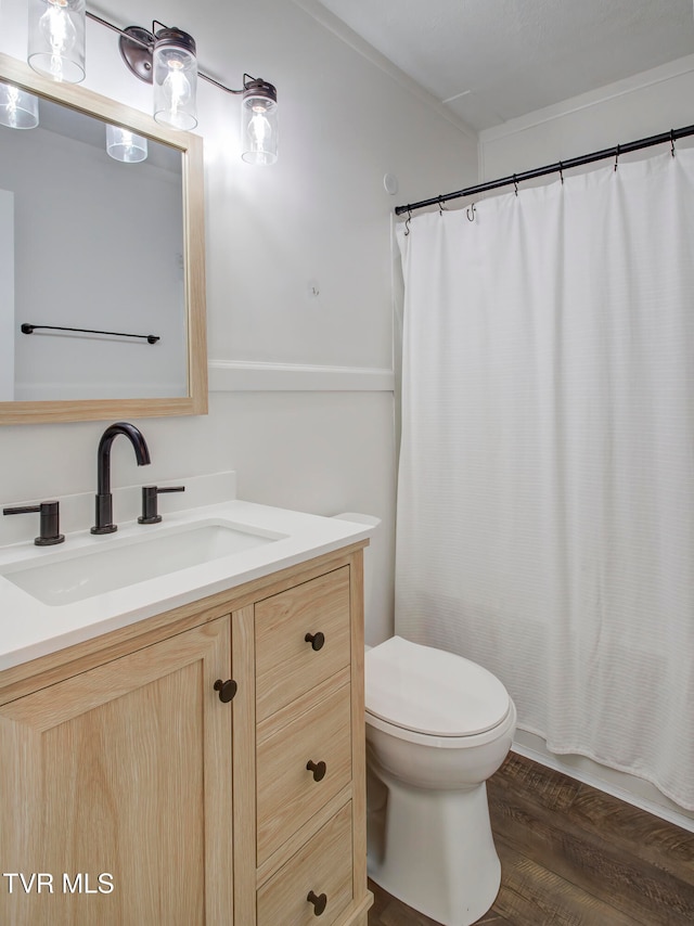 bathroom with toilet, vanity, and wood finished floors