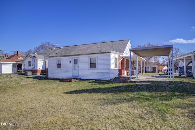 rear view of house with a patio, central AC unit, roof with shingles, a yard, and a carport