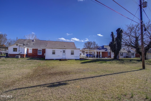 back of property featuring entry steps, a yard, central AC unit, and brick siding