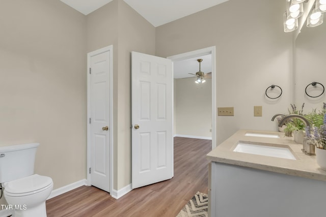 bathroom with vanity, ceiling fan with notable chandelier, hardwood / wood-style floors, and toilet