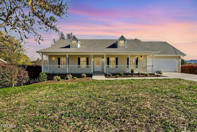 view of front facade featuring a garage, covered porch, and a lawn