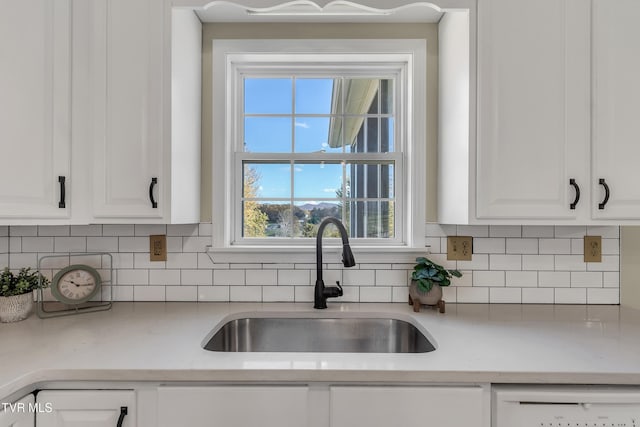 kitchen with white dishwasher, light stone countertops, sink, and white cabinets