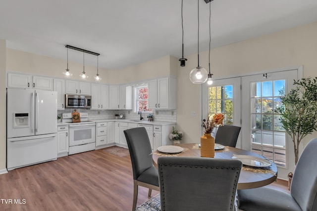 kitchen with pendant lighting, sink, white cabinets, decorative backsplash, and white appliances