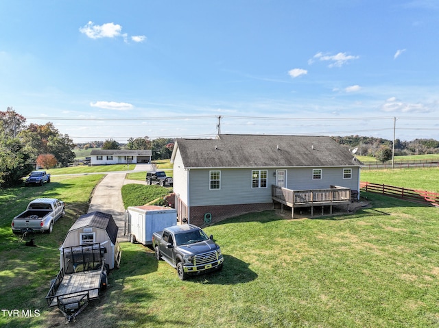 back of property with a yard, a deck, and a storage unit