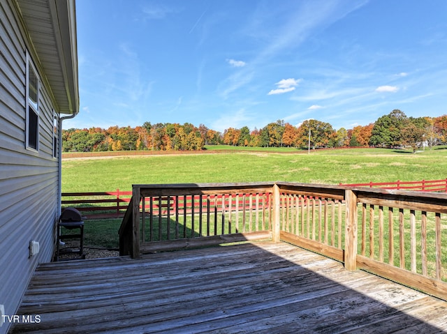 deck with a grill, a lawn, and a rural view