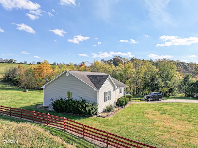 view of side of property with a yard, cooling unit, and a rural view