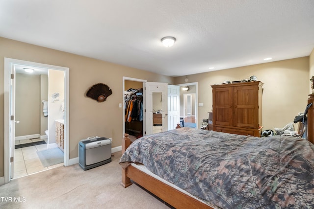 carpeted bedroom with a spacious closet, ensuite bath, a closet, and a textured ceiling