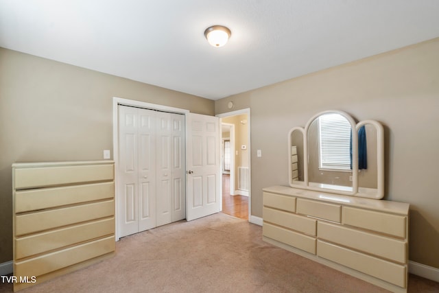 unfurnished bedroom with a closet and light colored carpet