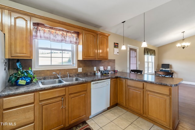 kitchen with kitchen peninsula, lofted ceiling, dishwasher, plenty of natural light, and sink