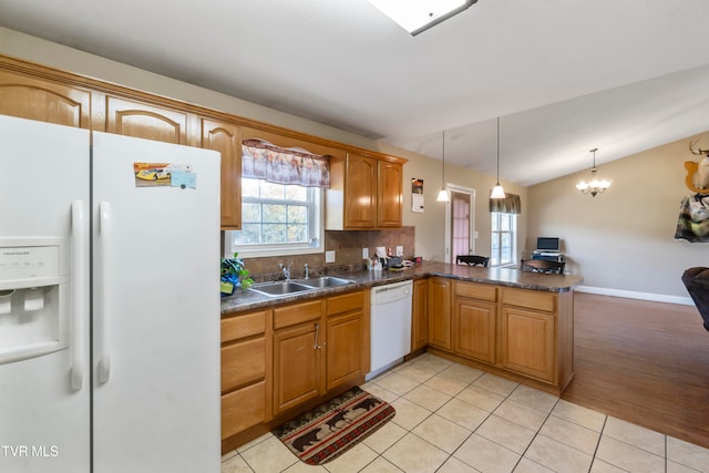 kitchen featuring white appliances, kitchen peninsula, light hardwood / wood-style floors, lofted ceiling, and decorative light fixtures