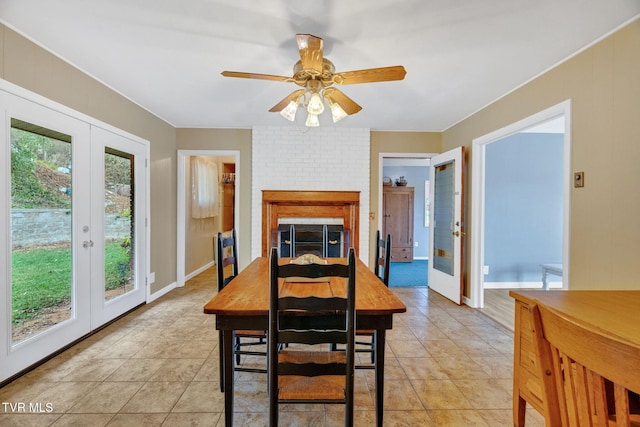 dining space with a fireplace, light tile patterned flooring, ceiling fan, and french doors