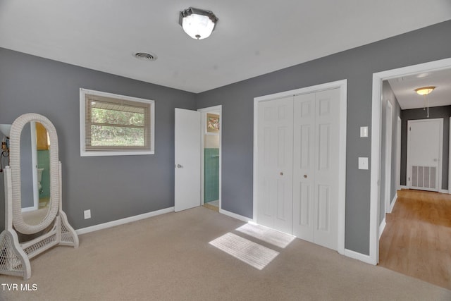 unfurnished bedroom with light carpet and a closet