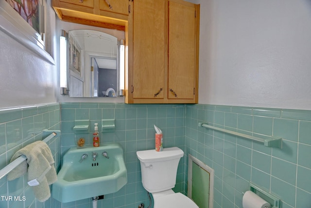 bathroom with sink, toilet, and tile walls