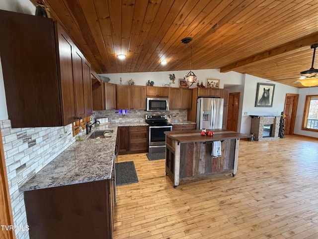 kitchen with a kitchen island, lofted ceiling with beams, decorative light fixtures, light wood-type flooring, and appliances with stainless steel finishes