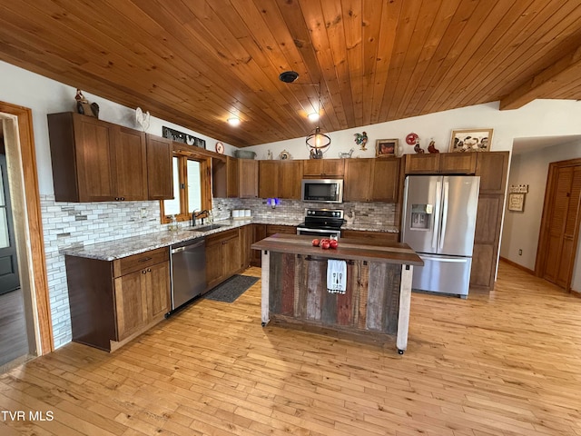 kitchen with vaulted ceiling, appliances with stainless steel finishes, and light wood-type flooring