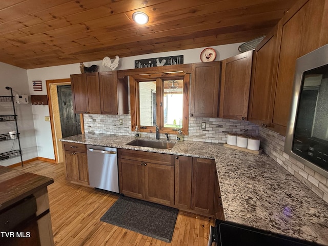 kitchen featuring decorative backsplash, sink, light stone countertops, light wood-type flooring, and appliances with stainless steel finishes