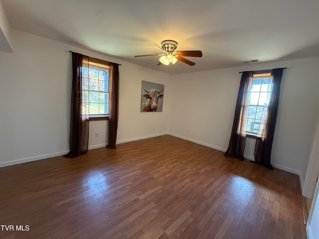 spare room with a wealth of natural light, ceiling fan, and dark hardwood / wood-style flooring