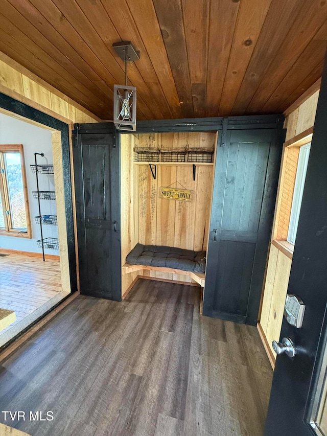 mudroom with wood walls, wooden ceiling, dark hardwood / wood-style flooring, and a barn door