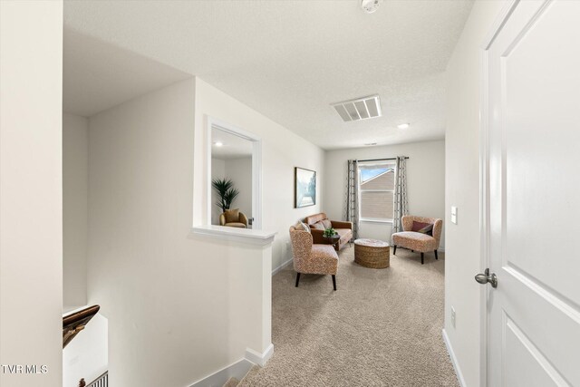 sitting room featuring light colored carpet and a textured ceiling