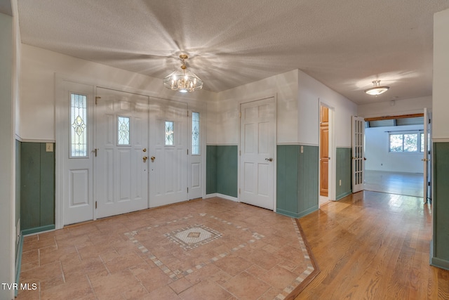 foyer entrance with a textured ceiling, wood-type flooring, and an inviting chandelier