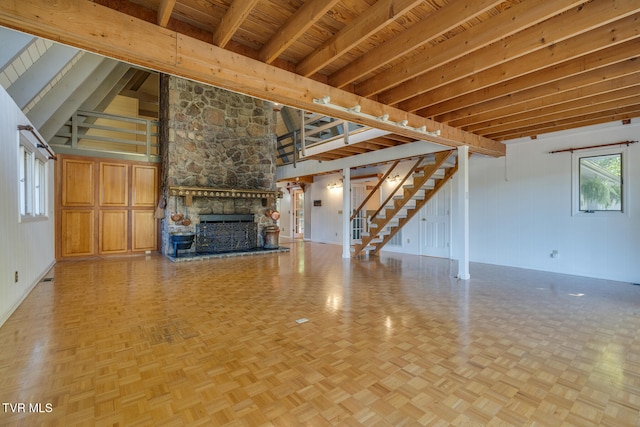 unfurnished living room with beamed ceiling, a stone fireplace, light parquet flooring, and wood ceiling