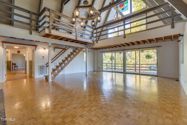 unfurnished living room with beamed ceiling, parquet floors, and high vaulted ceiling