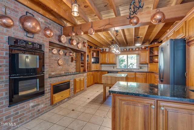 kitchen featuring black appliances, a center island, brick wall, and pendant lighting