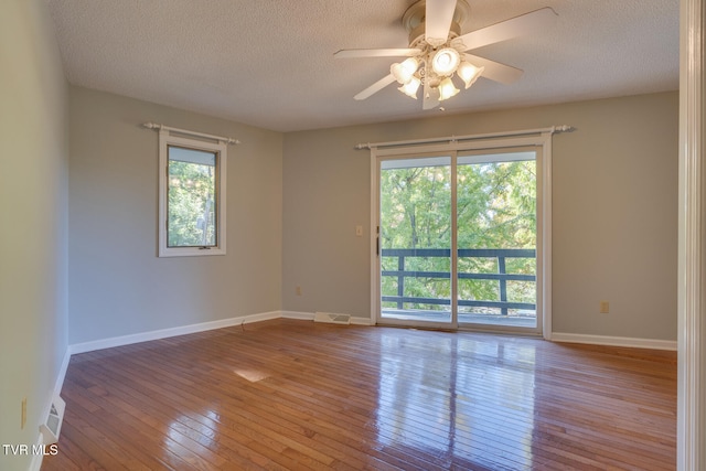 unfurnished room with ceiling fan, a textured ceiling, and light wood-type flooring