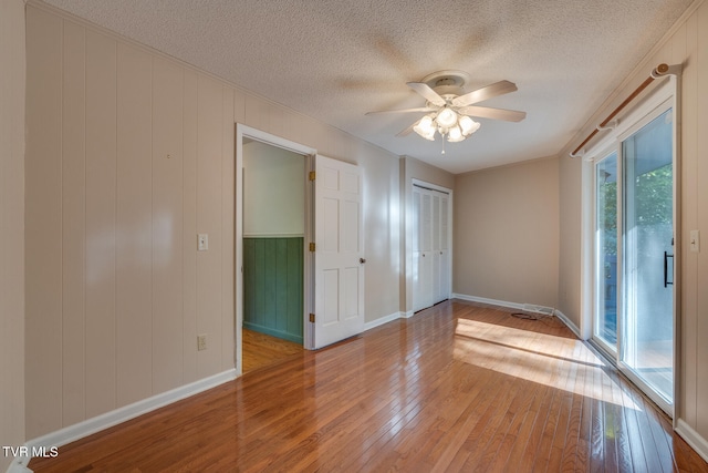 empty room with light hardwood / wood-style floors, a textured ceiling, and ceiling fan