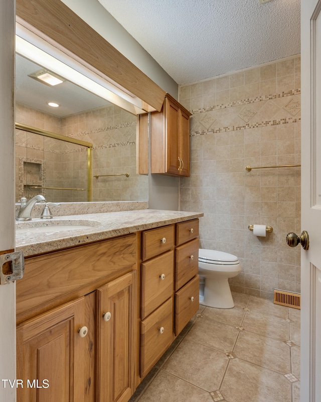 bathroom featuring tile walls, vanity, a textured ceiling, and toilet