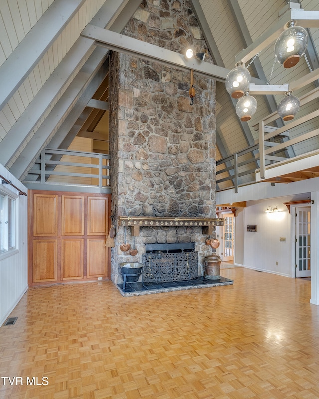 unfurnished living room featuring beam ceiling, light parquet floors, a fireplace, high vaulted ceiling, and wood walls