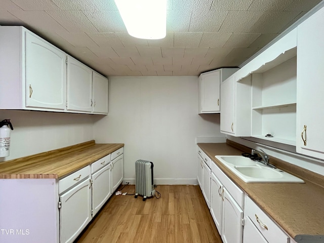 kitchen featuring sink, white cabinetry, light hardwood / wood-style flooring, and radiator heating unit