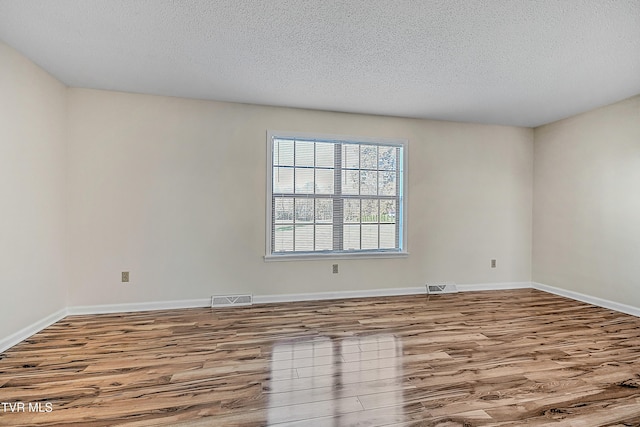 unfurnished room with light hardwood / wood-style flooring and a textured ceiling