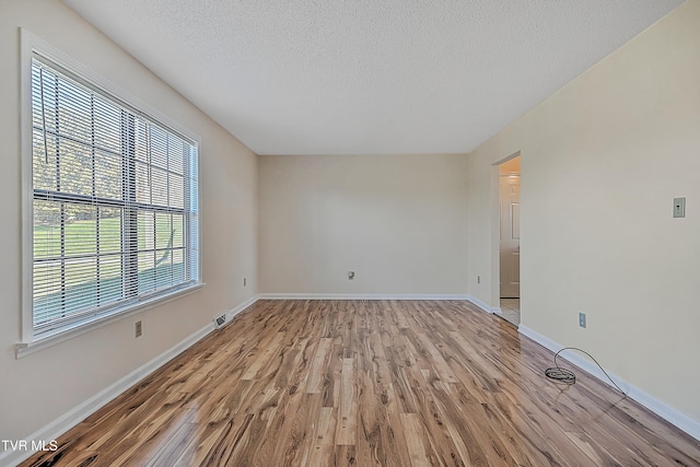 unfurnished room with light hardwood / wood-style floors and a textured ceiling