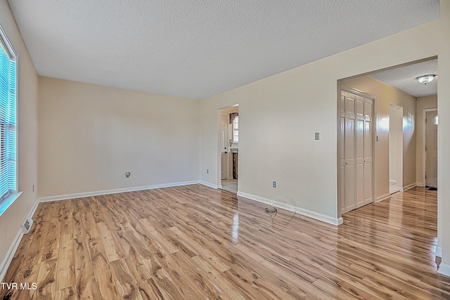 unfurnished room with a textured ceiling and light wood-type flooring