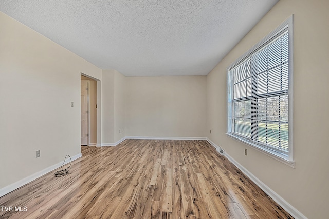 spare room with a textured ceiling and light wood-type flooring