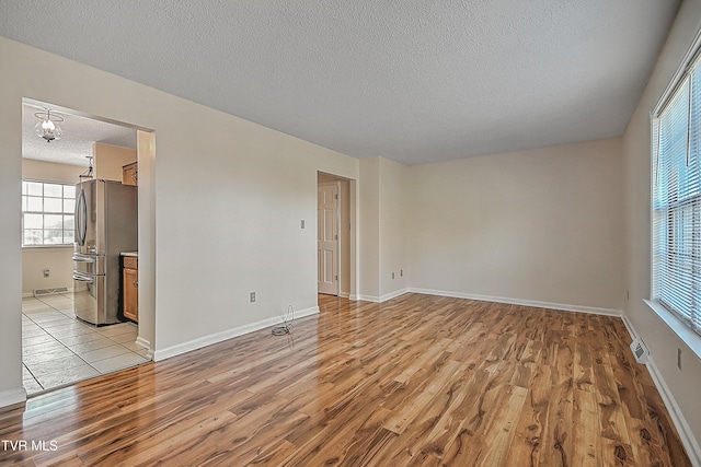 empty room with a textured ceiling and light hardwood / wood-style floors