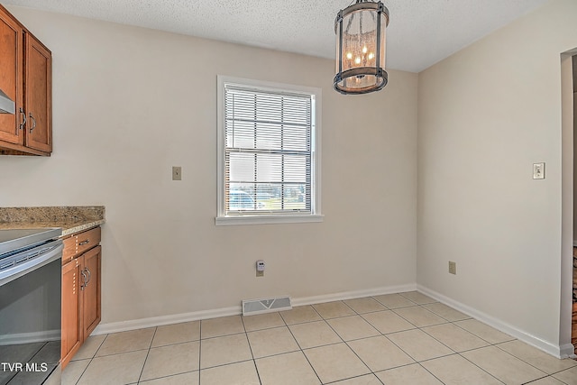 unfurnished dining area featuring a textured ceiling, light tile patterned floors, and a chandelier