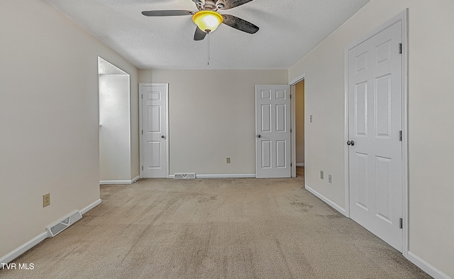 empty room featuring light carpet, a textured ceiling, and ceiling fan