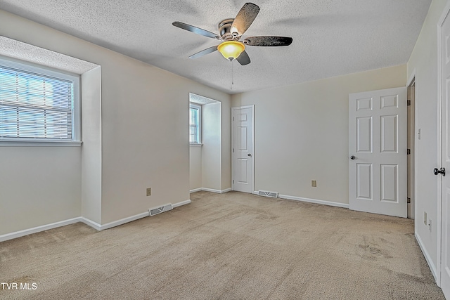 empty room with light carpet, a textured ceiling, and ceiling fan