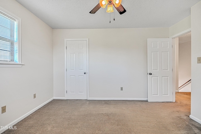 spare room featuring a textured ceiling, light colored carpet, and ceiling fan