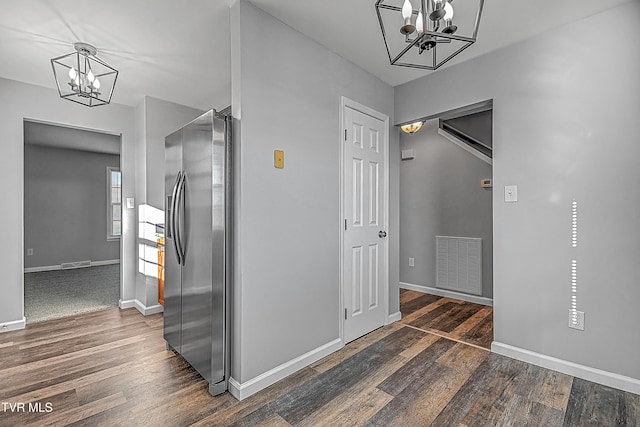 hallway with dark wood-type flooring and a chandelier