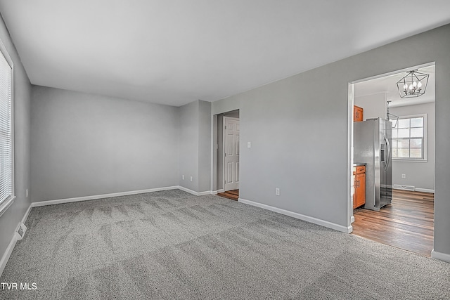 carpeted empty room featuring a notable chandelier