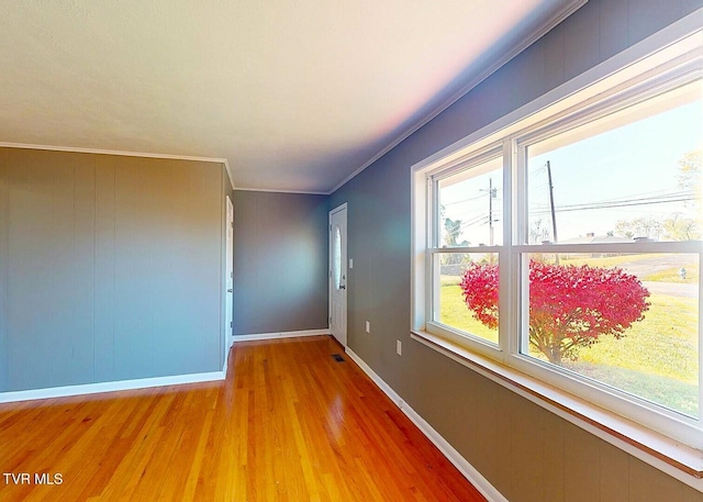 unfurnished room with crown molding, wood walls, and wood-type flooring