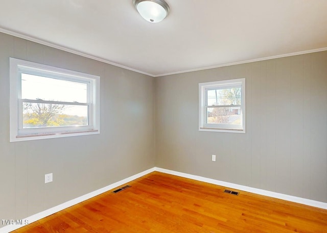 spare room featuring ornamental molding, wooden walls, and wood-type flooring