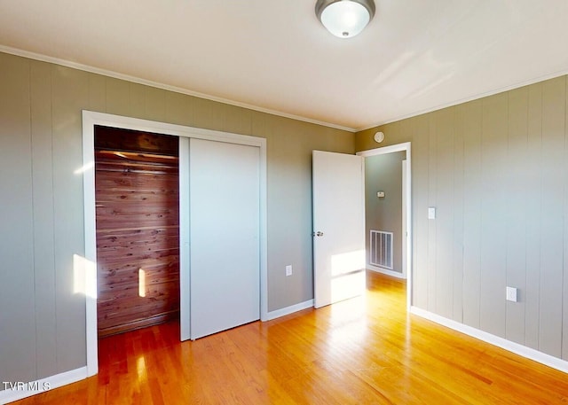 unfurnished bedroom featuring a closet, wood walls, and wood-type flooring