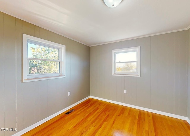 spare room with wood-type flooring, a healthy amount of sunlight, and wood walls