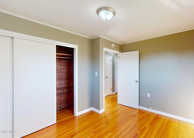 unfurnished bedroom featuring ornamental molding, hardwood / wood-style floors, a closet, and wooden walls