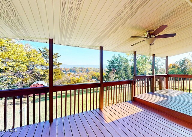 wooden terrace featuring ceiling fan and a lawn